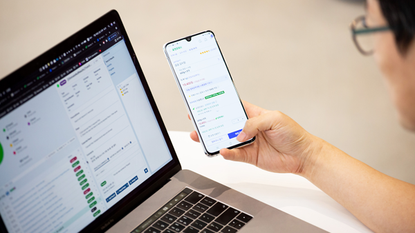 노트북 옆에서 휴대폰을 들고 있는 손