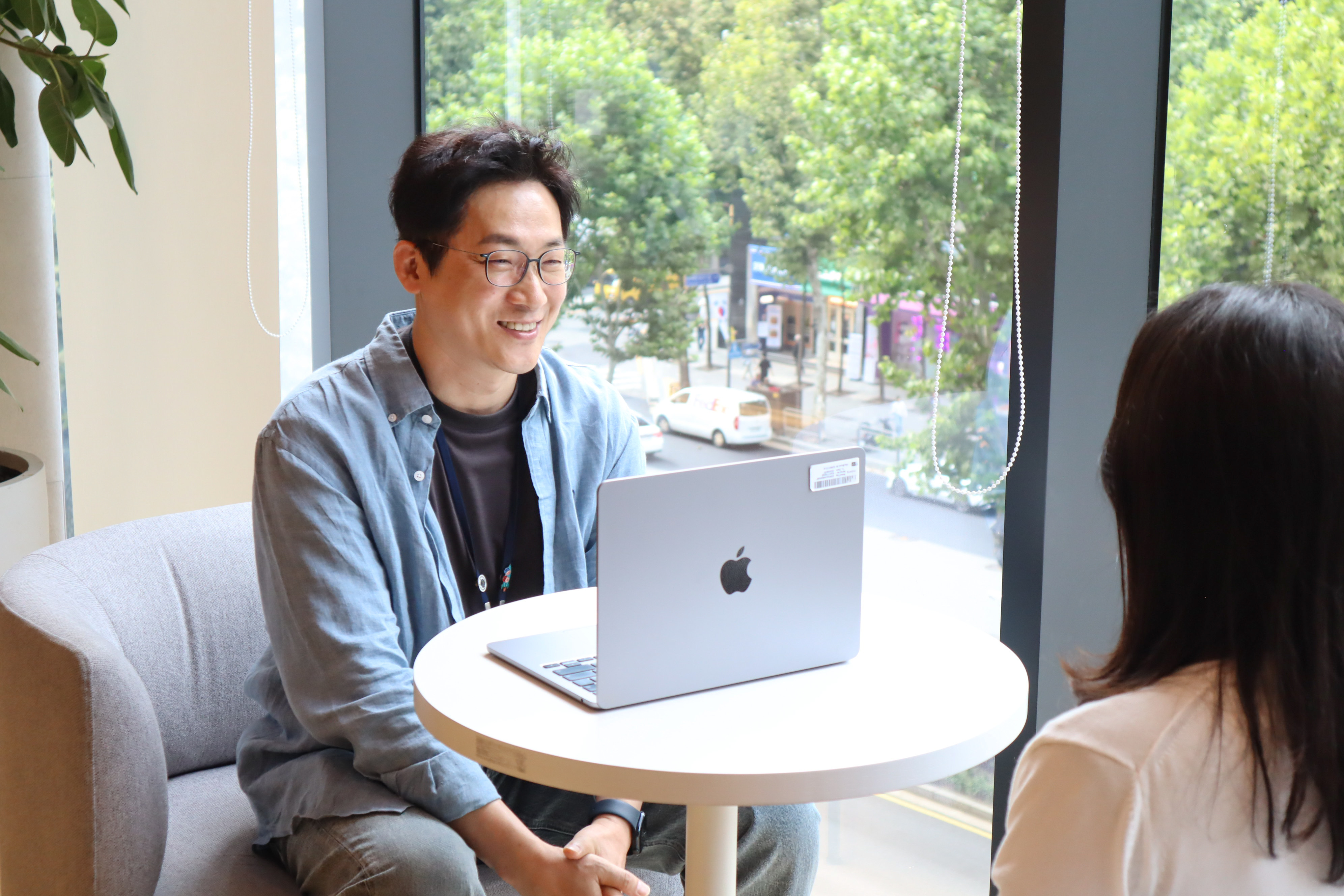 노트북을 들고 테이블에 앉아 있는 사람