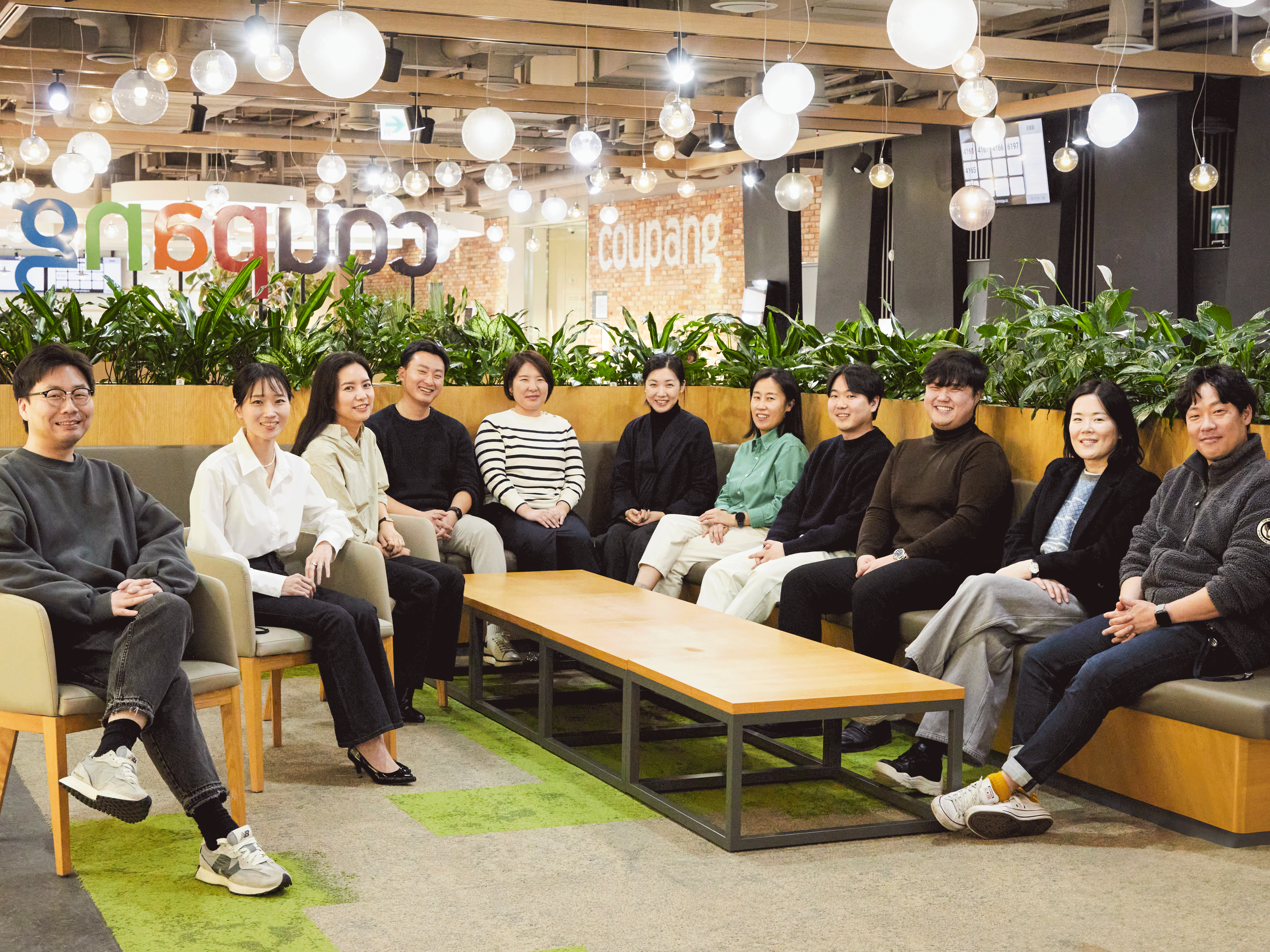 a group of people sitting on chairs in a room with plants