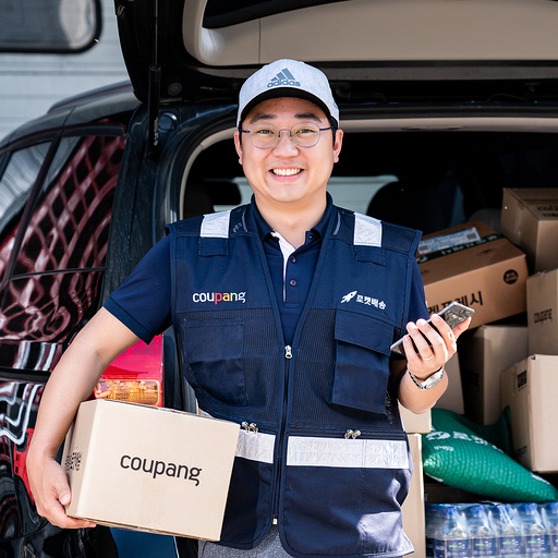 제복을 입은 사람이 상자와 전화기를 들고 있다