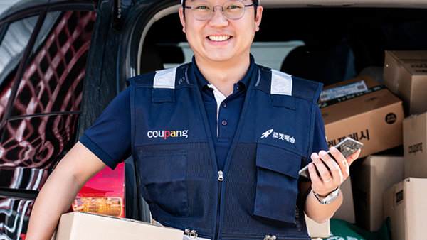 제복을 입은 사람이 상자와 전화기를 들고 있다