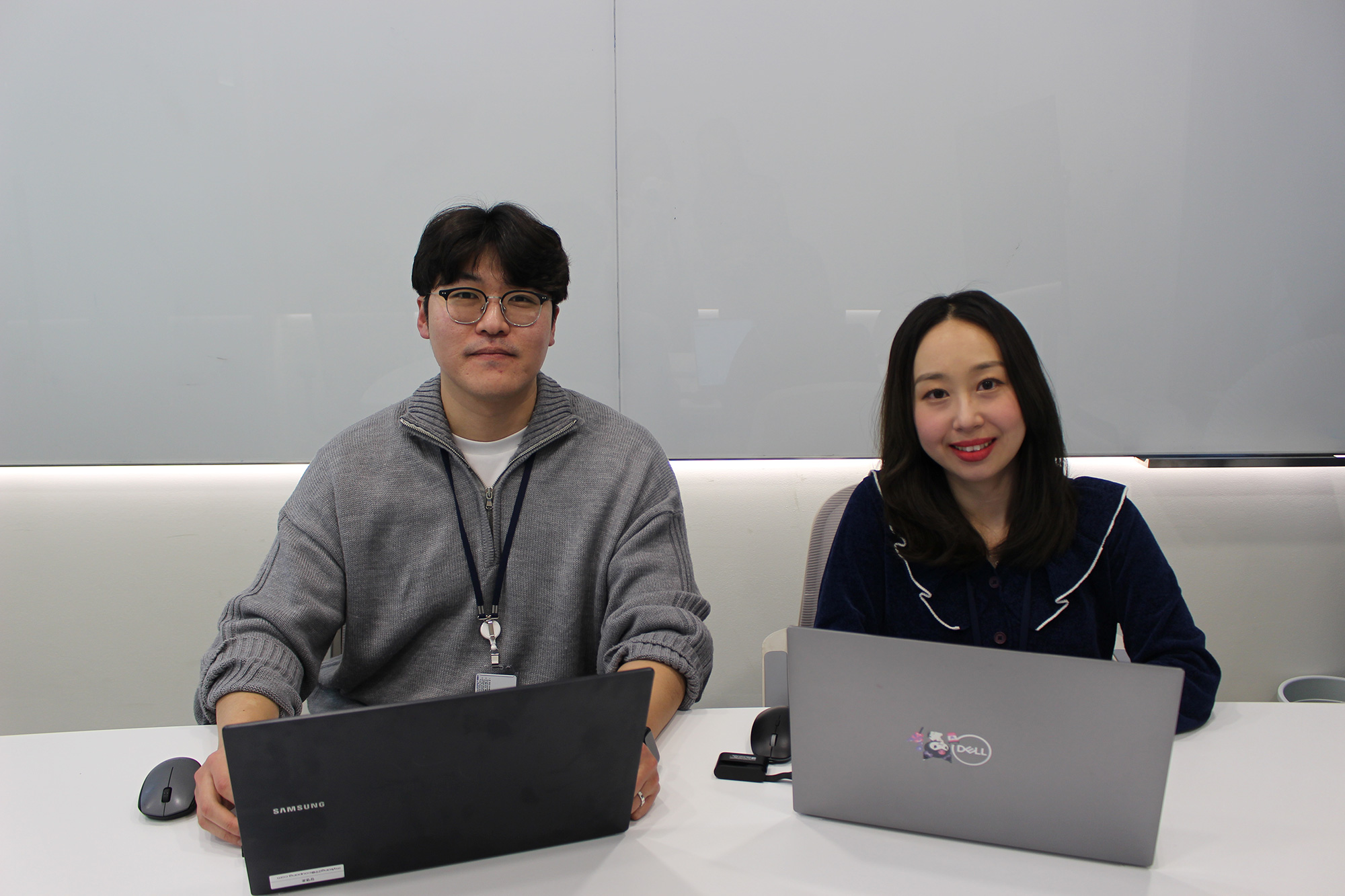 a person and person sitting at a table with laptops