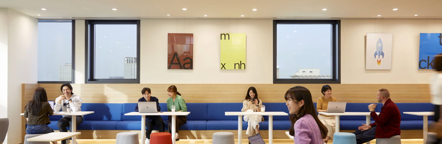 a group of people sitting in a room with tables and chairs