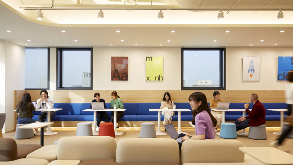 a group of people sitting in a room with tables and chairs